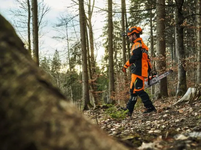 skovhugger i skov med motorsav, beskyttelseshjelm og stihl bukser advance flextec