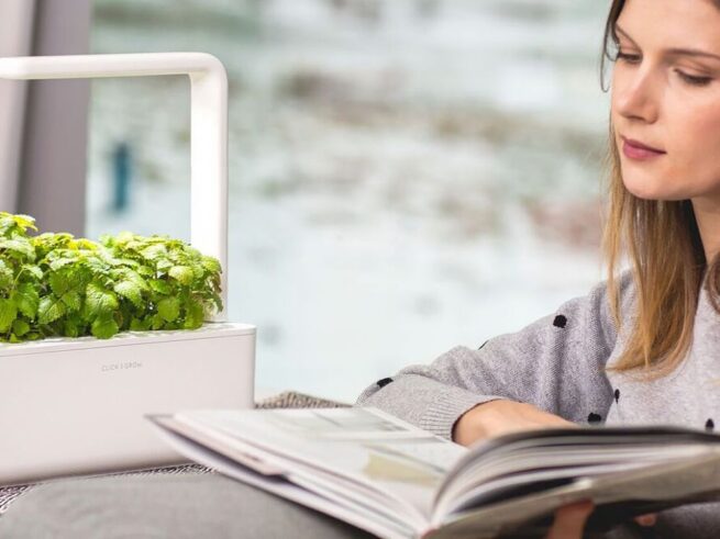 kvinde læser i bog, og i baggrunden ses en hvid click and grow smart garden 3
