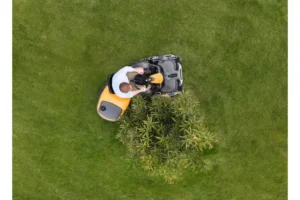 mand på stiga frontklipper demonstrerer knækstyring ved at klippe græa rundet om busk